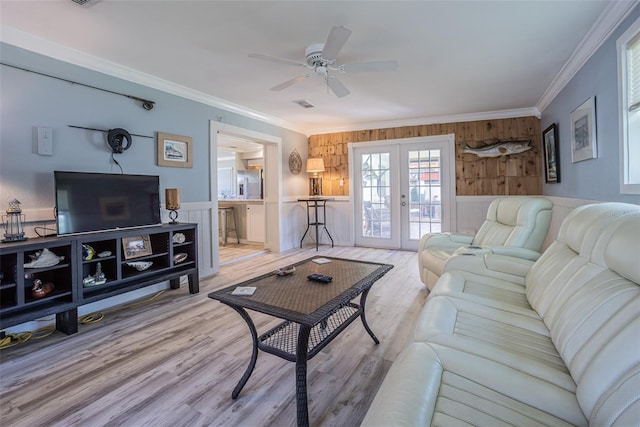 living area with crown molding, french doors, a ceiling fan, wood finished floors, and wooden walls