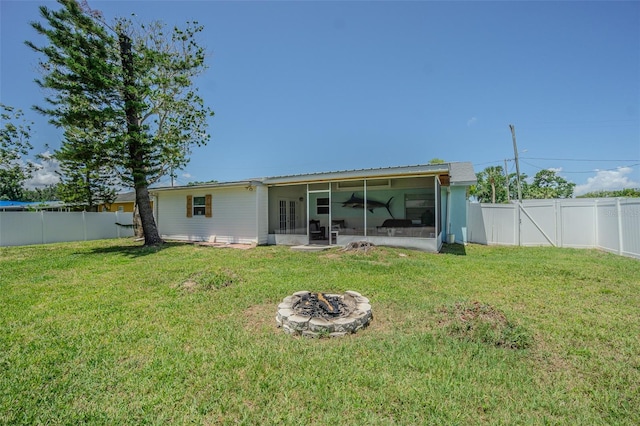 rear view of property featuring a sunroom and a fire pit