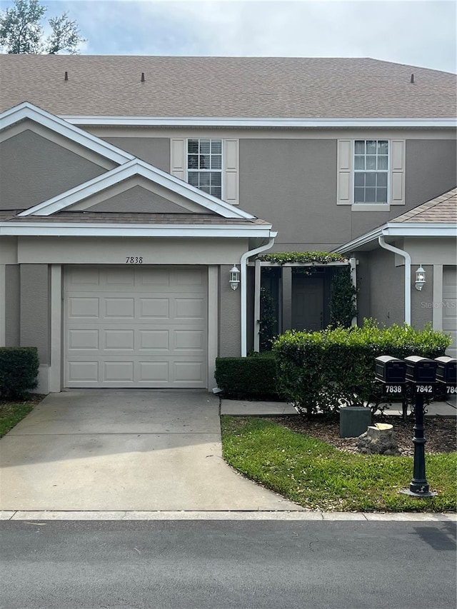 view of front of home featuring concrete driveway, stucco siding, a garage, and a shingled roof