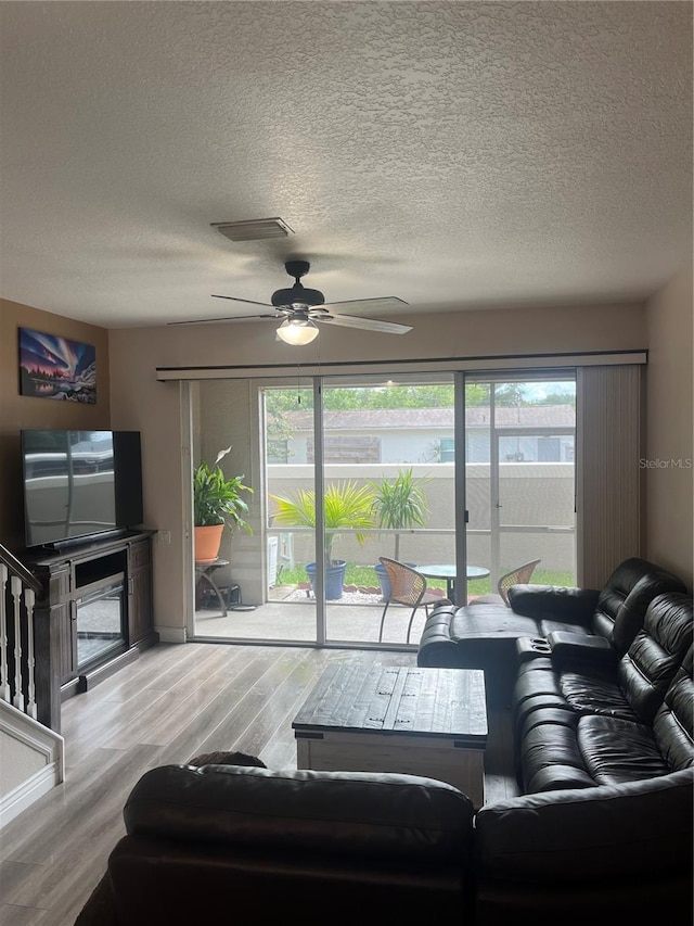 living area with wood finished floors, a ceiling fan, and a textured ceiling