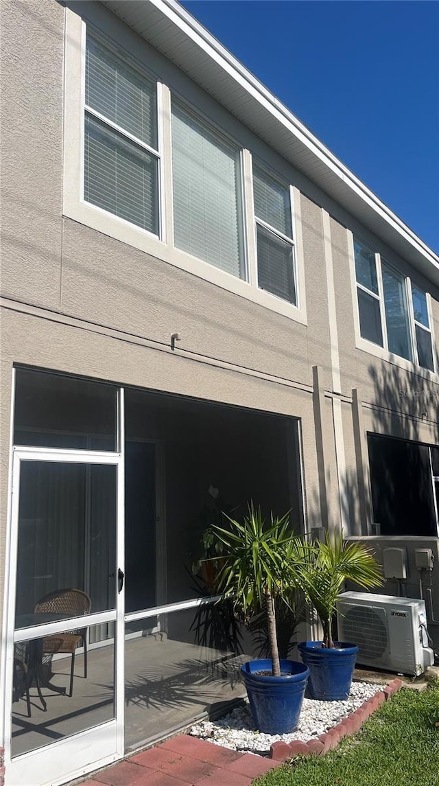 rear view of house with a cooling unit and stucco siding