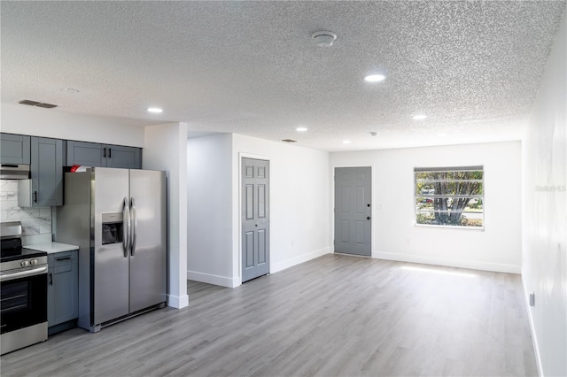 kitchen with stainless steel appliances, under cabinet range hood, a textured ceiling, light wood finished floors, and recessed lighting