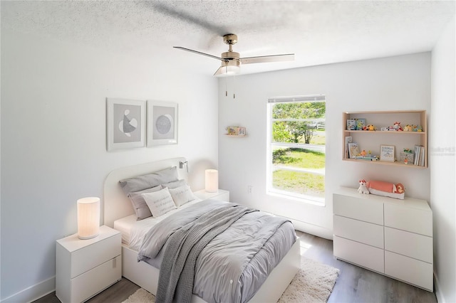 bedroom with wood finished floors, a textured ceiling, and a ceiling fan