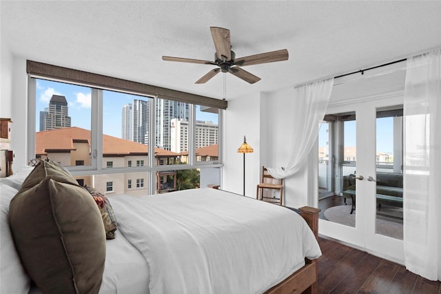 bedroom featuring a city view, hardwood / wood-style floors, french doors, and a ceiling fan
