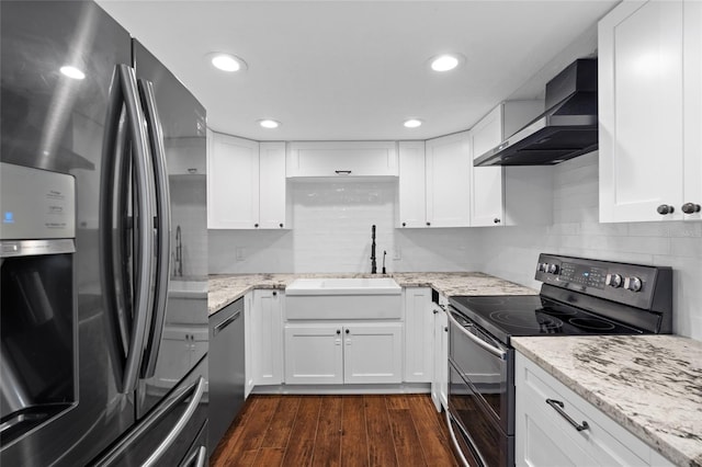 kitchen featuring appliances with stainless steel finishes, wall chimney exhaust hood, a sink, white cabinets, and recessed lighting