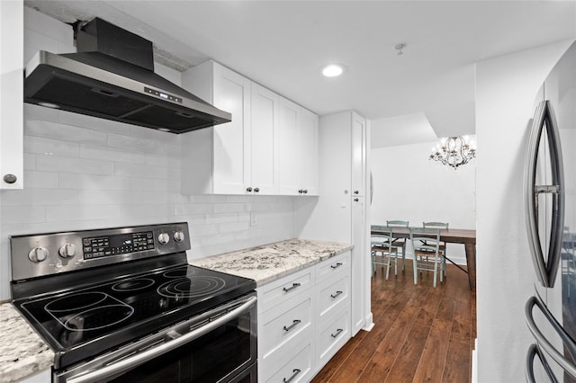 kitchen with appliances with stainless steel finishes, wall chimney exhaust hood, a chandelier, tasteful backsplash, and white cabinetry