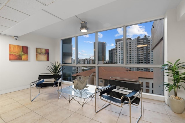 living room featuring a view of city, tile patterned flooring, baseboards, and floor to ceiling windows