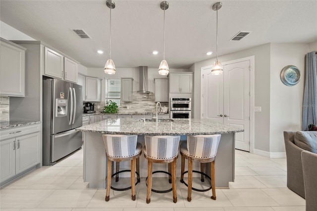 31643 Colada Drift Way, Wesley Chapel, FL 33545 - kitchen featuring appliances with stainless steel finishes, wall chimney range hood, a sink, decorative backsplash, and a breakfast bar