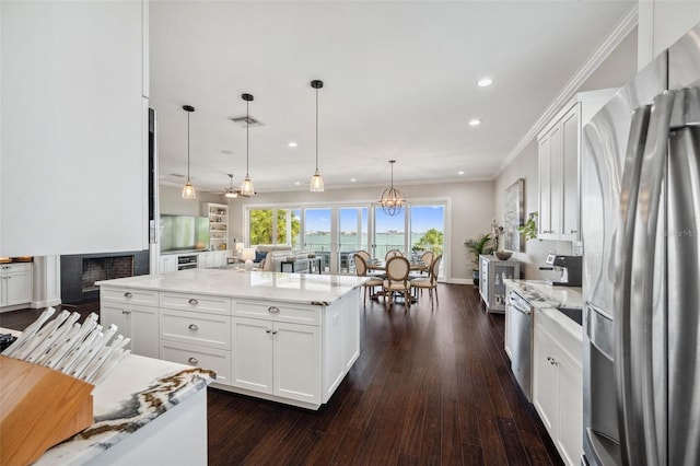 7115 Bay St, St Pete Beach, FL 33706 - kitchen with stainless steel refrigerator with ice dispenser, white cabinets, recessed lighting, light stone counters, and pendant lighting
