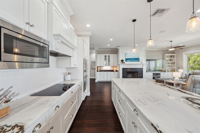 7115 Bay St, St Pete Beach, FL 33706 - kitchen with appliances with stainless steel finishes, white cabinets, dark wood-type flooring, tasteful backsplash, and ceiling fan