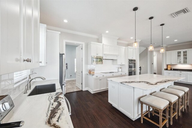 7115 Bay St, St Pete Beach, FL 33706 - kitchen with a sink, stainless steel appliances, white cabinetry, a center island, and dark wood-style floors