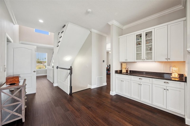 7115 Bay St, St Pete Beach, FL 33706 - kitchen with dark countertops, glass insert cabinets, dark wood-style floors, baseboards, and white cabinetry