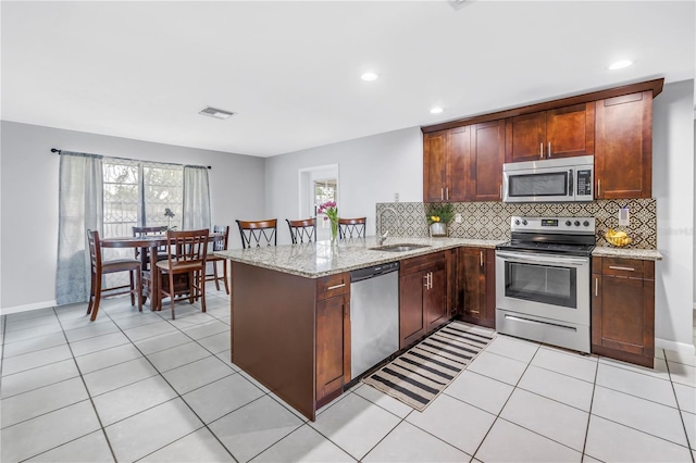 2270 Amherst Ave, Spring Hill, FL 34609 - kitchen featuring stainless steel appliances, a sink, a peninsula, tasteful backsplash, and light stone counters