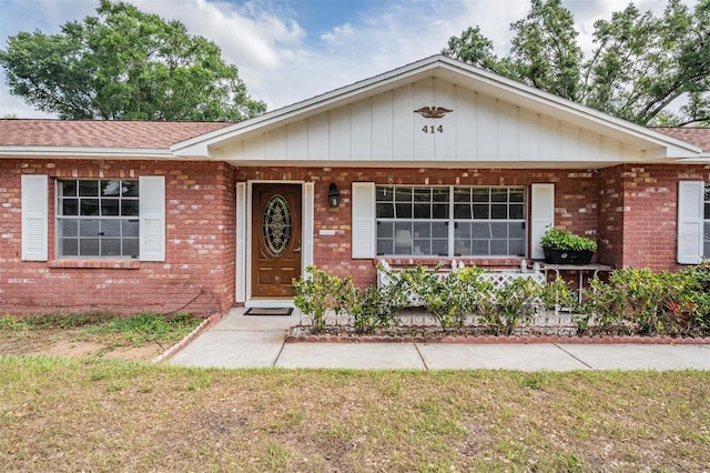 single story home featuring brick siding, a porch, and a shingled roof