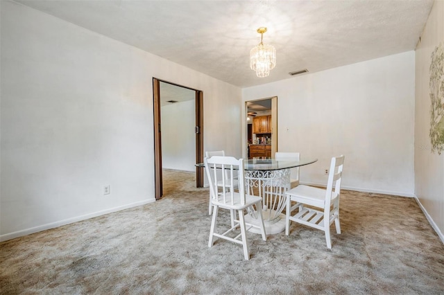 carpeted dining room with a chandelier and baseboards