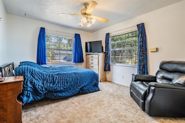 carpeted bedroom with multiple windows, ceiling fan, and baseboards