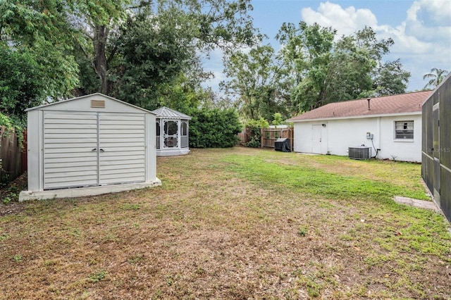 view of yard with a storage shed, an outbuilding, central AC, and view of wooded area