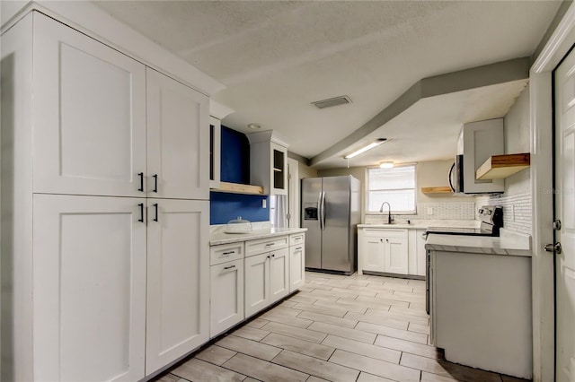 9120 Lunar Ln, Port Richey, FL 34668 - kitchen featuring stainless steel appliances, a sink, white cabinetry, glass insert cabinets, and backsplash