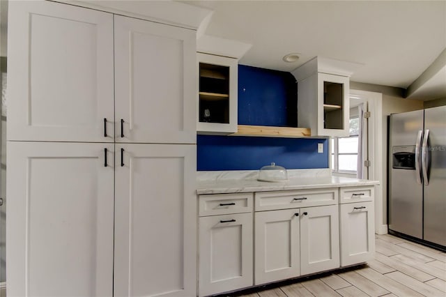 9120 Lunar Ln, Port Richey, FL 34668 - kitchen featuring stainless steel refrigerator with ice dispenser, open shelves, white cabinetry, and light stone countertops