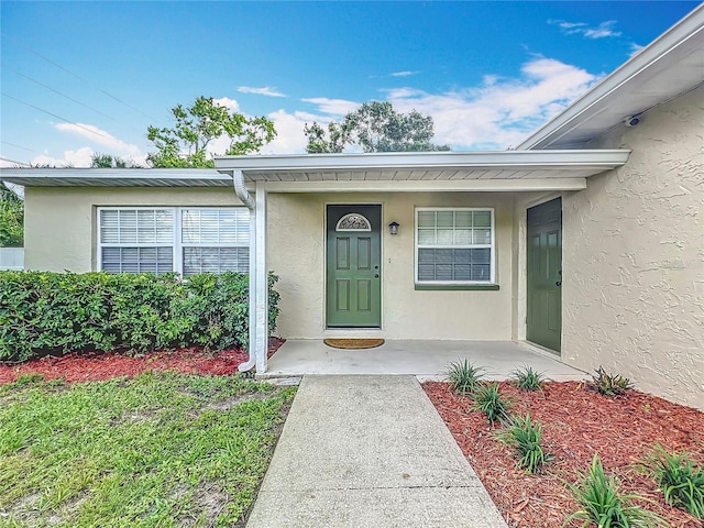doorway to property featuring stucco siding and covered porch
