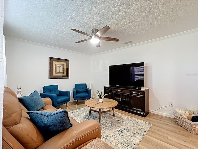 living room featuring crown molding, a ceiling fan, light wood-style flooring, a textured ceiling, and baseboards