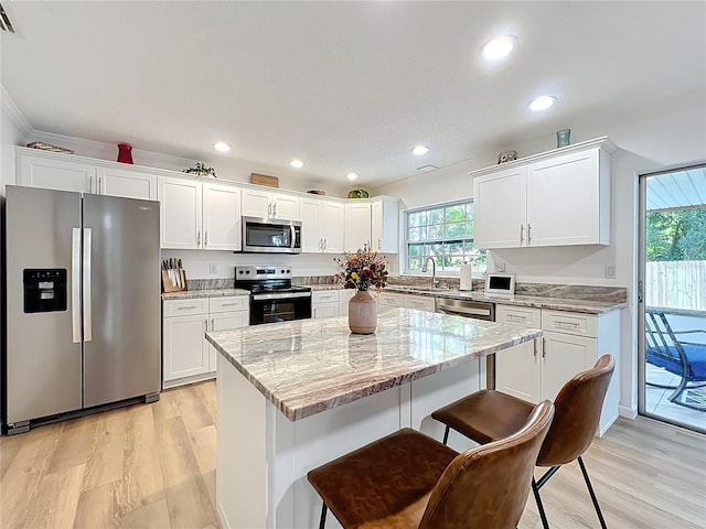 kitchen with stainless steel appliances, plenty of natural light, white cabinetry, a kitchen island, and recessed lighting
