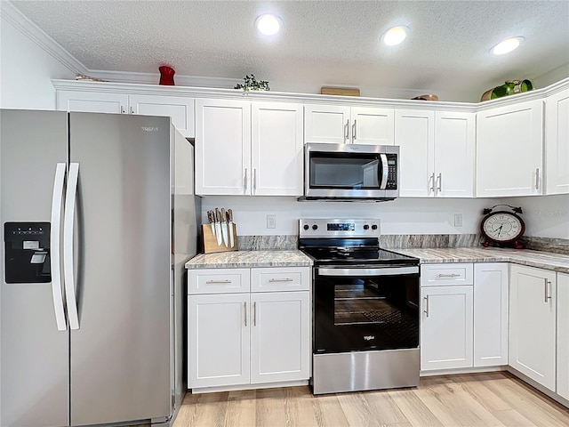 kitchen with stainless steel appliances, a textured ceiling, white cabinets, light wood-type flooring, and ornamental molding
