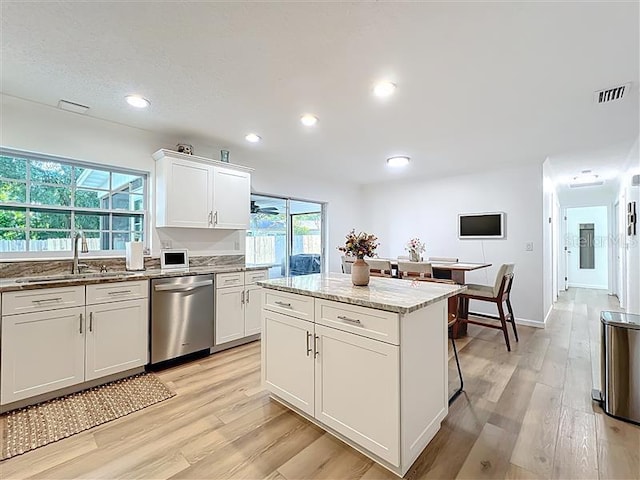 kitchen with dishwasher, a sink, light wood finished floors, light stone counters, and recessed lighting