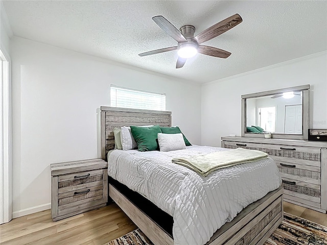 bedroom featuring light wood-style flooring, a textured ceiling, and a ceiling fan