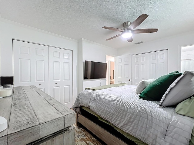 bedroom featuring a textured ceiling, a ceiling fan, and two closets