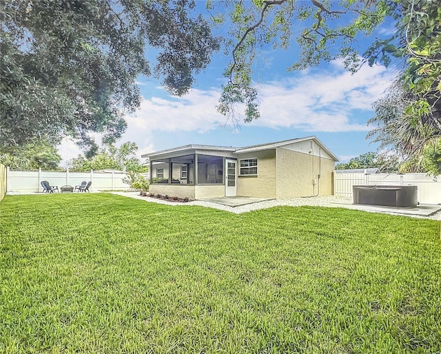 rear view of property featuring a sunroom, a hot tub, and stucco siding