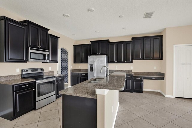 10106 Count Fleet Dr, Ruskin, FL 33575 - kitchen with appliances with stainless steel finishes, dark cabinets, a sink, light tile patterned floors, and a textured ceiling