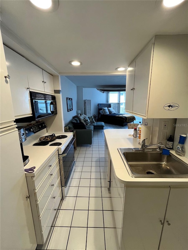 16400 Gulf Blvd Unit 307, North Redington Beach, FL 33708 - kitchen featuring range with electric cooktop, a sink, black microwave, light countertops, and light tile patterned floors