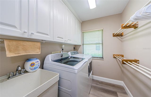 671 Tallahassee Dr NE, Saint Petersburg, FL 33702 - laundry room featuring washing machine and clothes dryer, cabinet space, light wood-style floors, and baseboards