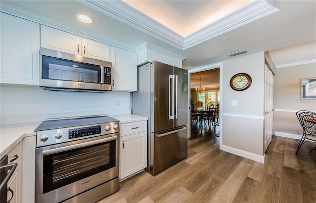 671 Tallahassee Dr NE, Saint Petersburg, FL 33702 - kitchen with stainless steel appliances, white cabinets, light countertops, light wood-type flooring, and ornamental molding