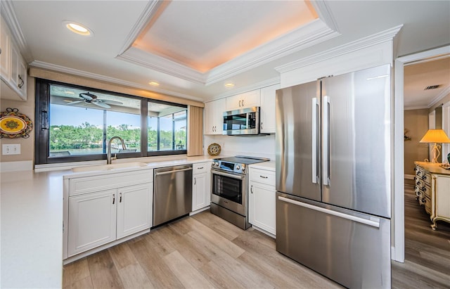 671 Tallahassee Dr NE, Saint Petersburg, FL 33702 - kitchen with stainless steel appliances, a sink, crown molding, white cabinets, and light wood-type flooring