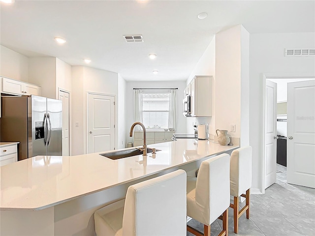 800 Reggie Rd, Winter Haven, FL 33884 - kitchen with stainless steel appliances, a sink, a breakfast bar area, white cabinets, and recessed lighting