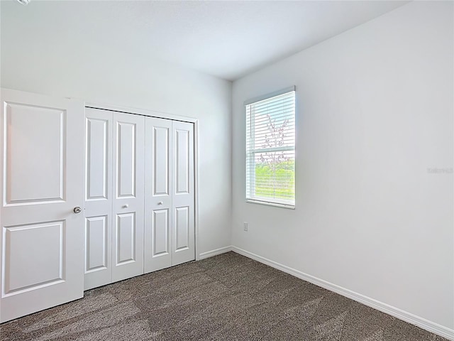 800 Reggie Rd, Winter Haven, FL 33884 - unfurnished bedroom featuring dark colored carpet, baseboards, and a closet