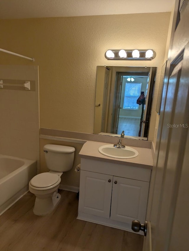 5915 Brickleberry Ln Unit 103, Zephyrhills, FL 33541 - bathroom with wood finished floors, vanity, toilet, tub / shower combination, and a textured wall