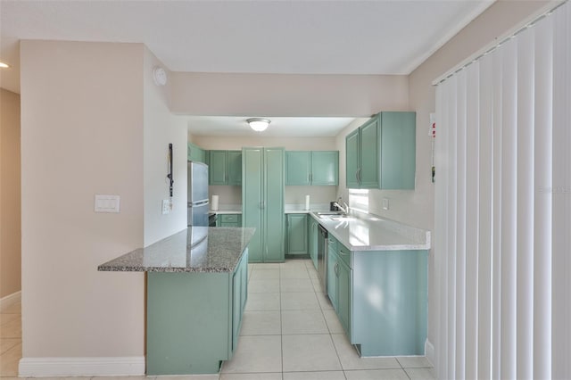 13125 Wilcox Rd Unit 16202, Largo, FL 33774 - kitchen featuring green cabinetry, stainless steel appliances, a sink, light tile patterned flooring, and stone countertops