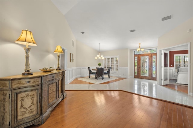 3922 Cedar Cay Cir, Valrico, FL 33596 - foyer with a chandelier, a wainscoted wall, vaulted ceiling, light wood finished floors, and a decorative wall