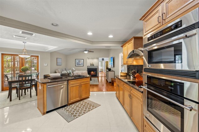 3922 Cedar Cay Cir, Valrico, FL 33596 - kitchen featuring stainless steel appliances, a sink, a warm lit fireplace, open floor plan, and a raised ceiling