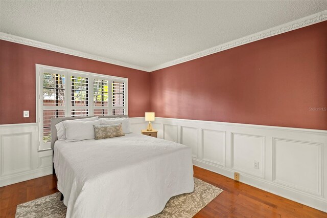 3922 Cedar Cay Cir, Valrico, FL 33596 - bedroom with a textured ceiling, wainscoting, wood finished floors, ornamental molding, and a decorative wall
