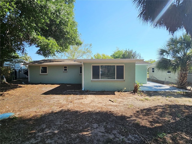 rear view of house with stucco siding, fence, and a patio area