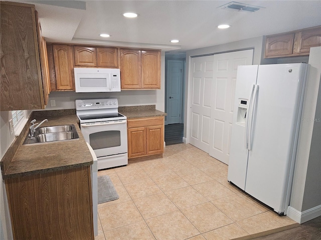 kitchen featuring white appliances, a sink, dark countertops, recessed lighting, and light tile patterned floors