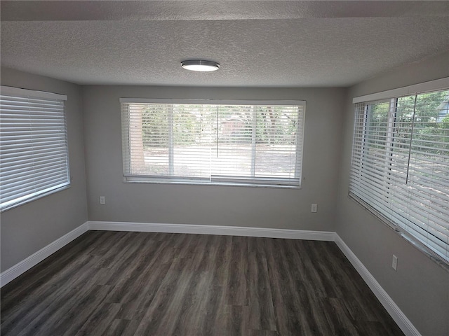unfurnished room featuring dark wood-style floors, a textured ceiling, and baseboards