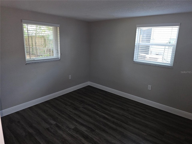 unfurnished room with dark wood-type flooring, baseboards, and a textured ceiling