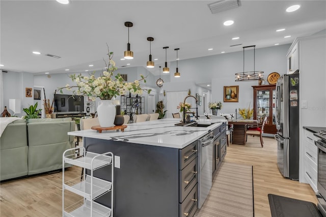 332 Wood Dove Ave, Tarpon Springs, FL 34689 - kitchen featuring stainless steel appliances, a sink, a breakfast bar area, light wood-style flooring, and a large island with sink