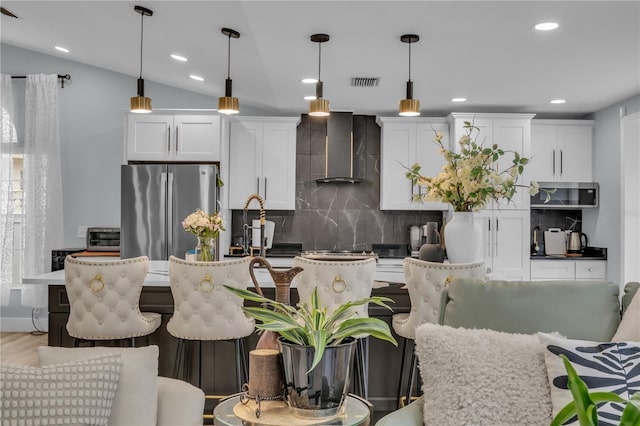 332 Wood Dove Ave, Tarpon Springs, FL 34689 - kitchen featuring wall chimney exhaust hood, stainless steel appliances, tasteful backsplash, white cabinetry, and decorative light fixtures
