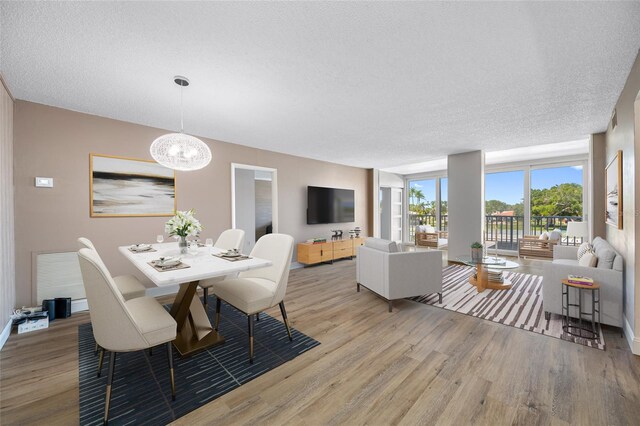10216 Regal Dr Unit 208, Largo, FL 33774 - dining room with light wood-style flooring, a textured ceiling, a chandelier, and baseboards
